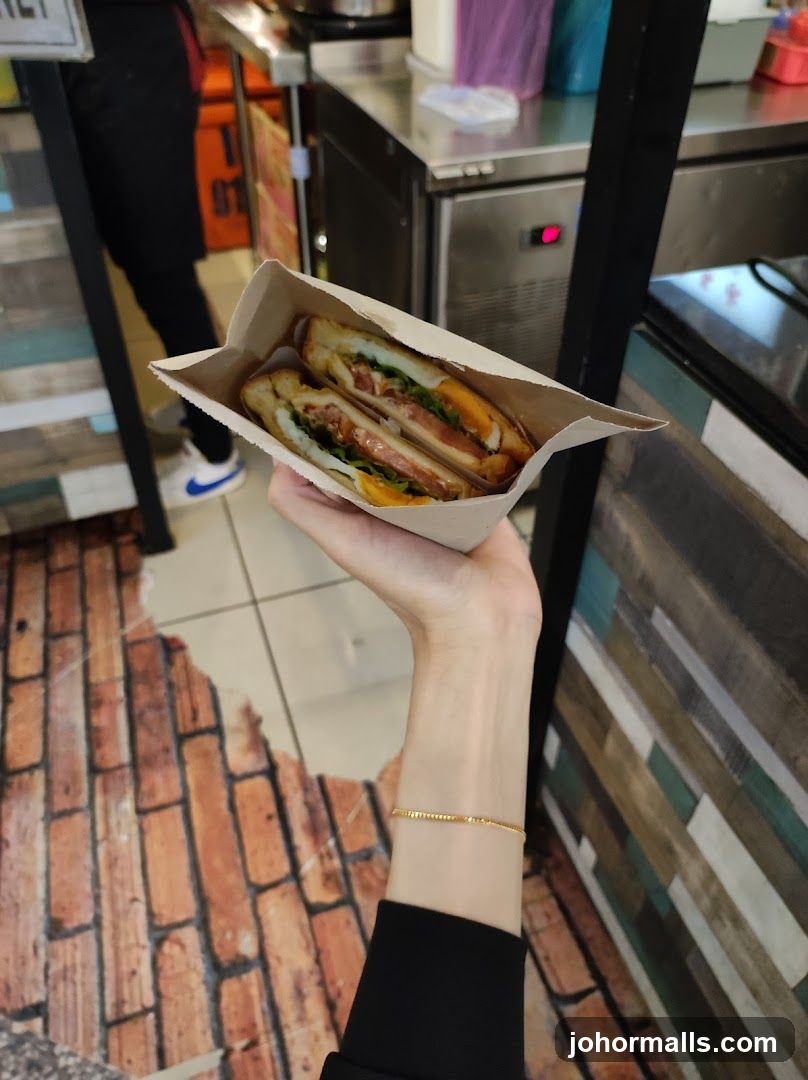 Hand holding sandwich in paper wrapper