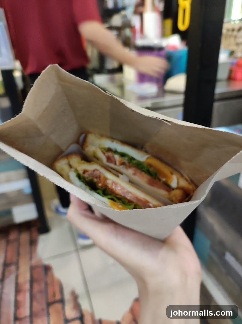 Hand holding sandwich in paper bag