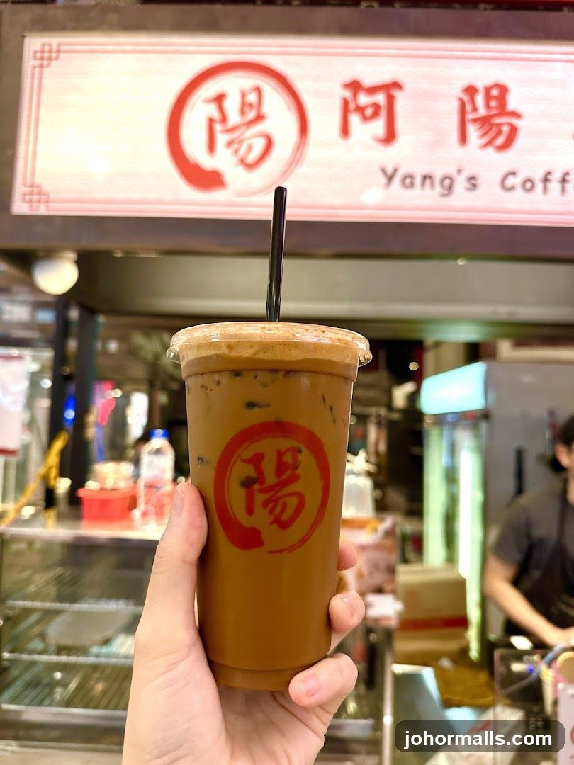 Hand holding iced coffee at Yang's Coffee