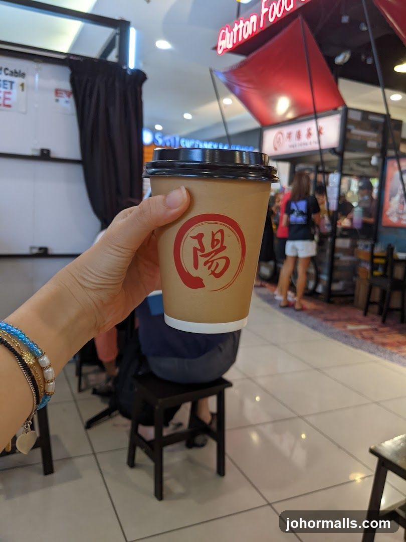 Hand holding coffee cup in food court