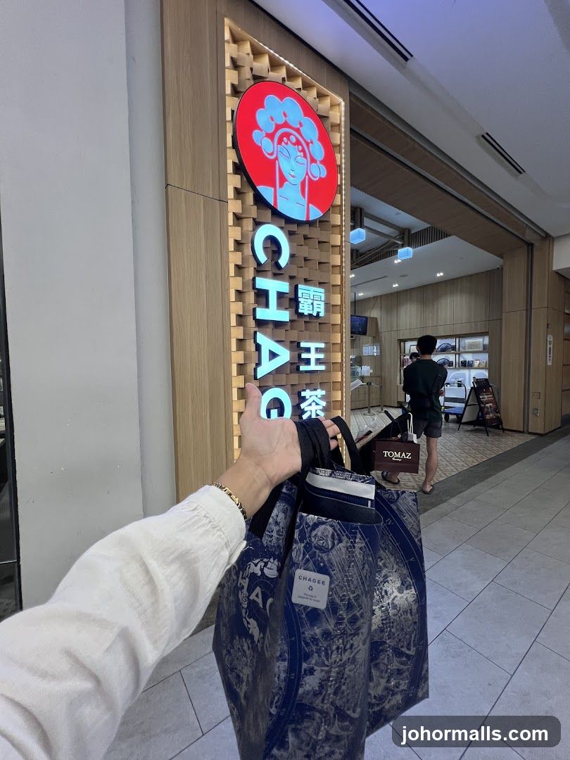 Hand holding shopping bag in front of store entrance