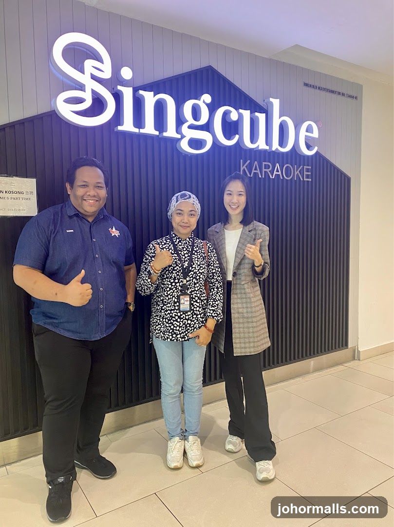 Three people posing in front of Singcube Karaoke signage