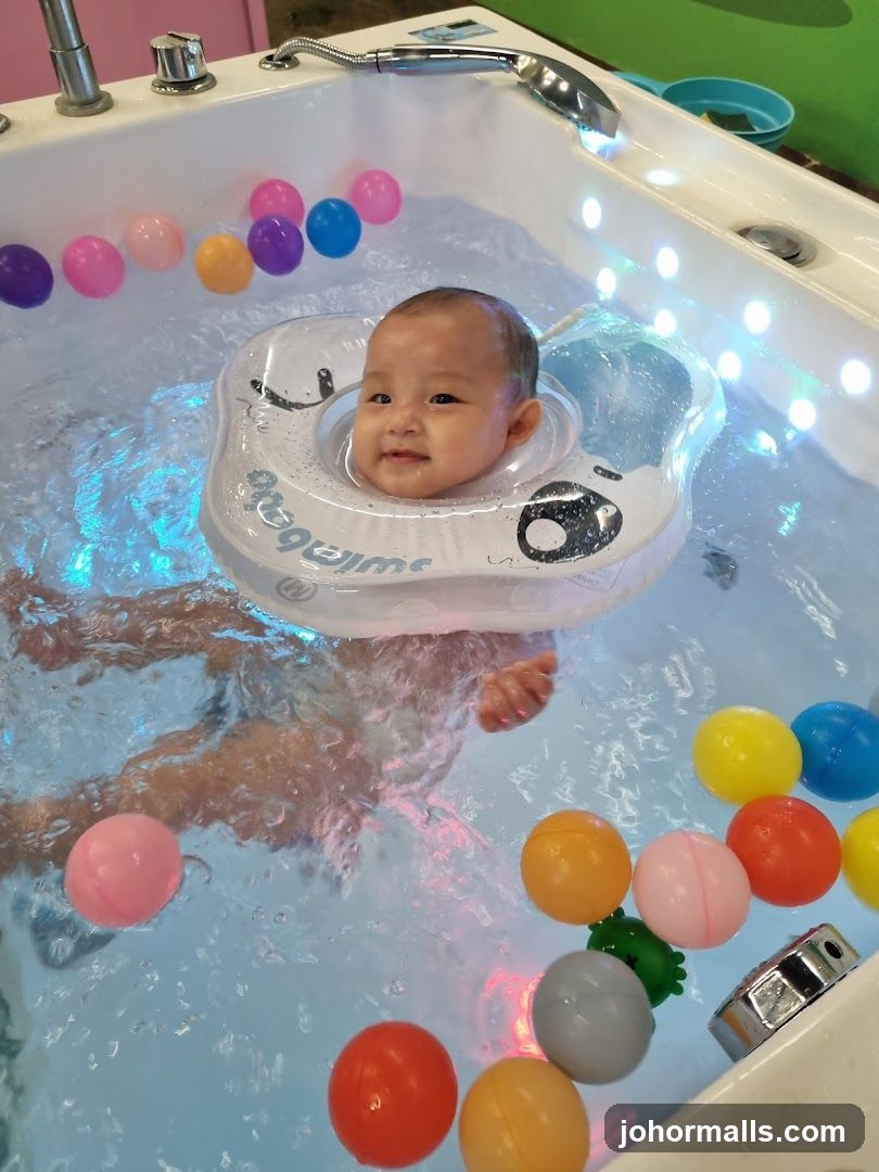Baby in inflatable bathtub with colorful balls