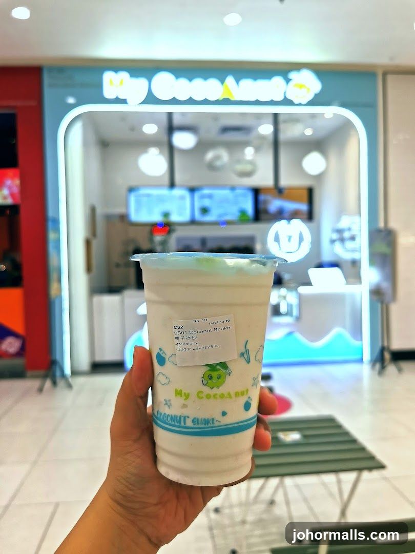 Hand holding a coconut shake in front of My CocoAnut shop