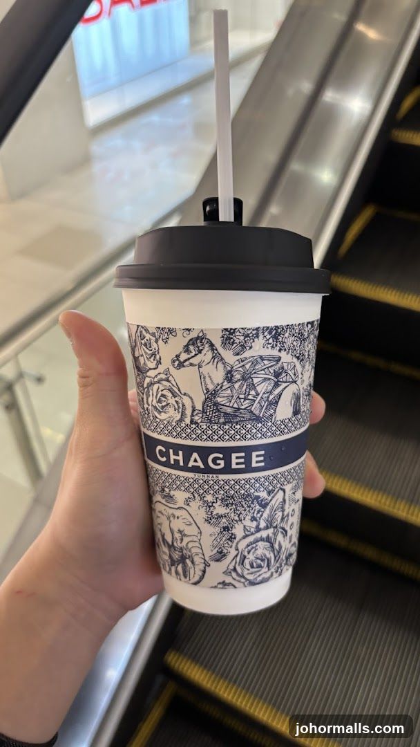 Hand holding Chagee drink on escalator