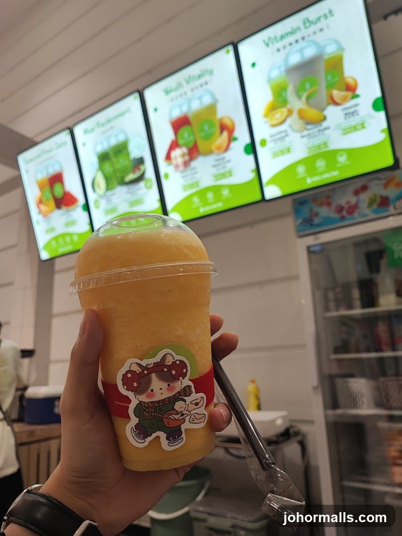 Hand holding a smoothie with menu boards in the background