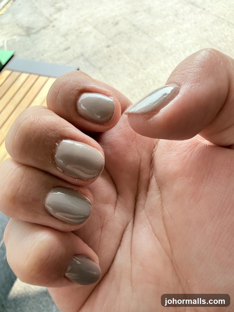 Close-up of a hand with taupe and light gray nail polish