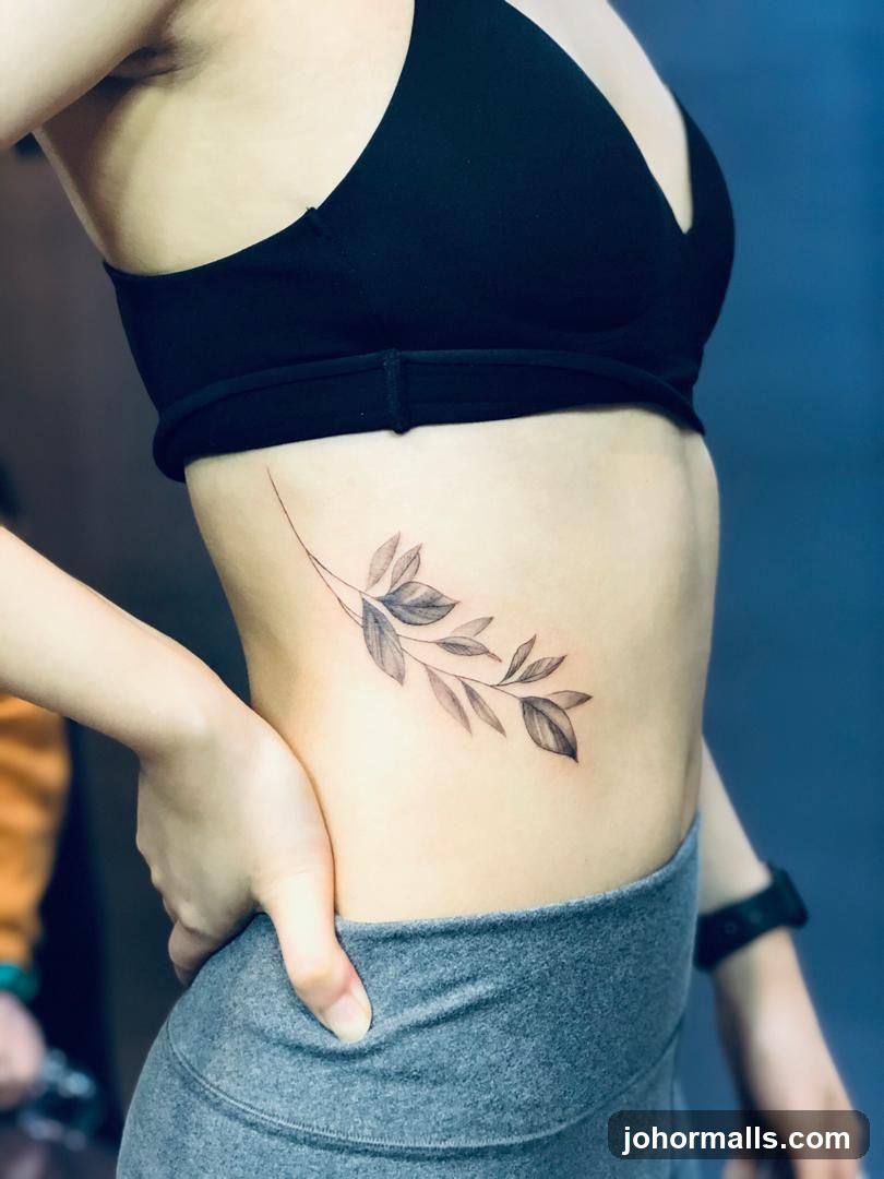 Tattoo of a branch with leaves on a person's side