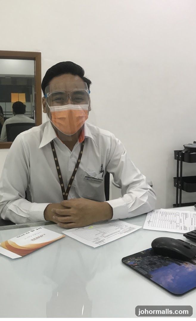 Man wearing face mask and shield at desk