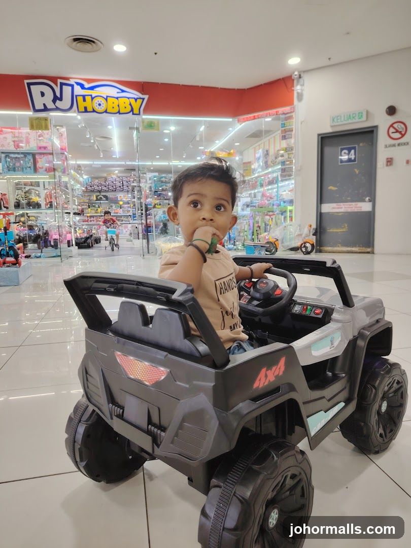 Child in toy car in front of toy store
