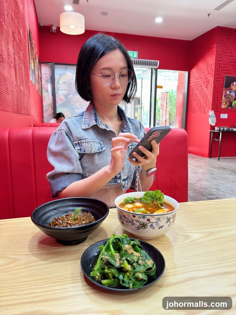 Woman using phone at restaurant table with food