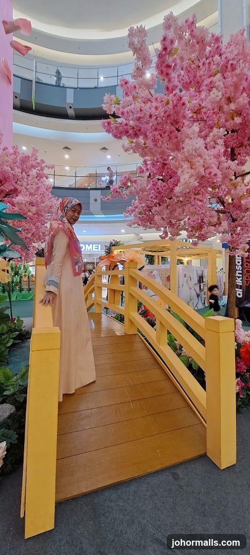 Woman posing on a decorative bridge with cherry blossoms