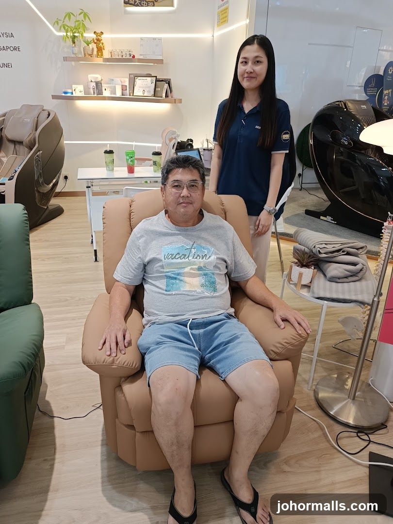 Man sitting in a massage chair with a sales associate standing behind him