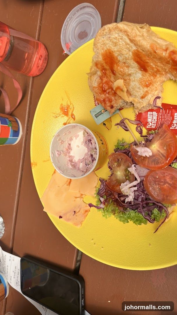 Half-eaten sandwich with sides on a yellow plate