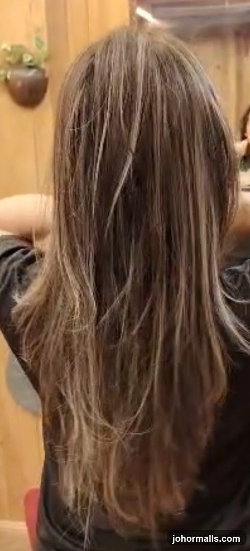 Woman with long, layered brown hair with blonde highlights