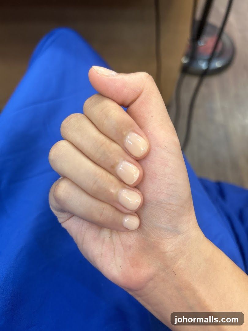 Close-up of a hand with light-colored nail polish