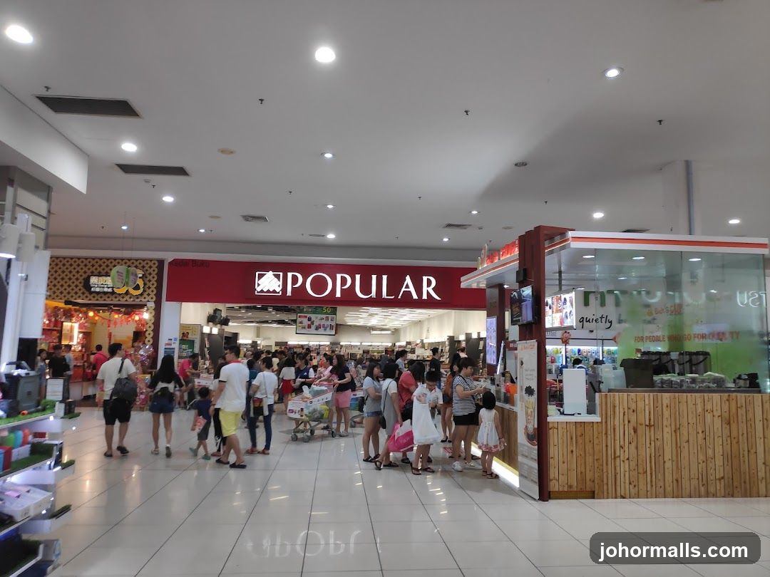 Busy shopping mall interior with a bookstore and a beverage stall