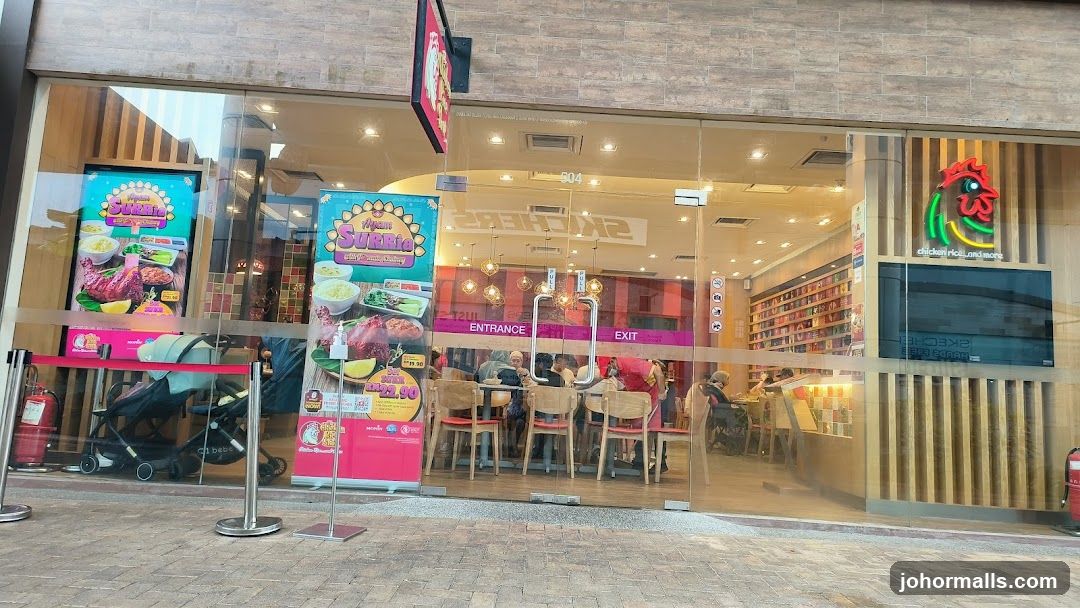 The exterior of a restaurant with large glass windows and doors. Inside, tables and chairs are visible, with customers seated. Promotional posters displaying food items are displayed on the windows. A neon sign of a chicken head with the text "chicken rice...and more" is visible on the right side of the facade. The word "SKECHERS" is reflected on the glass doors.