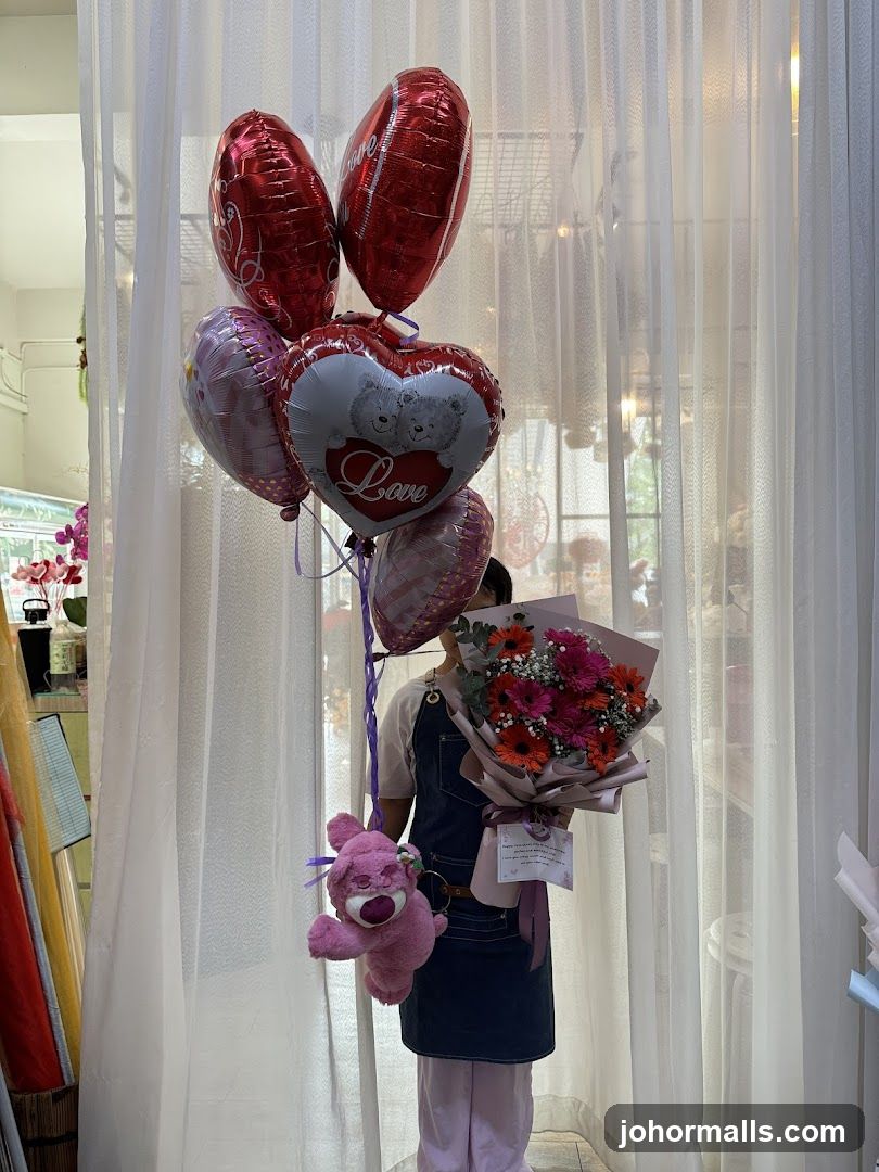 Person holding balloons and a bouquet