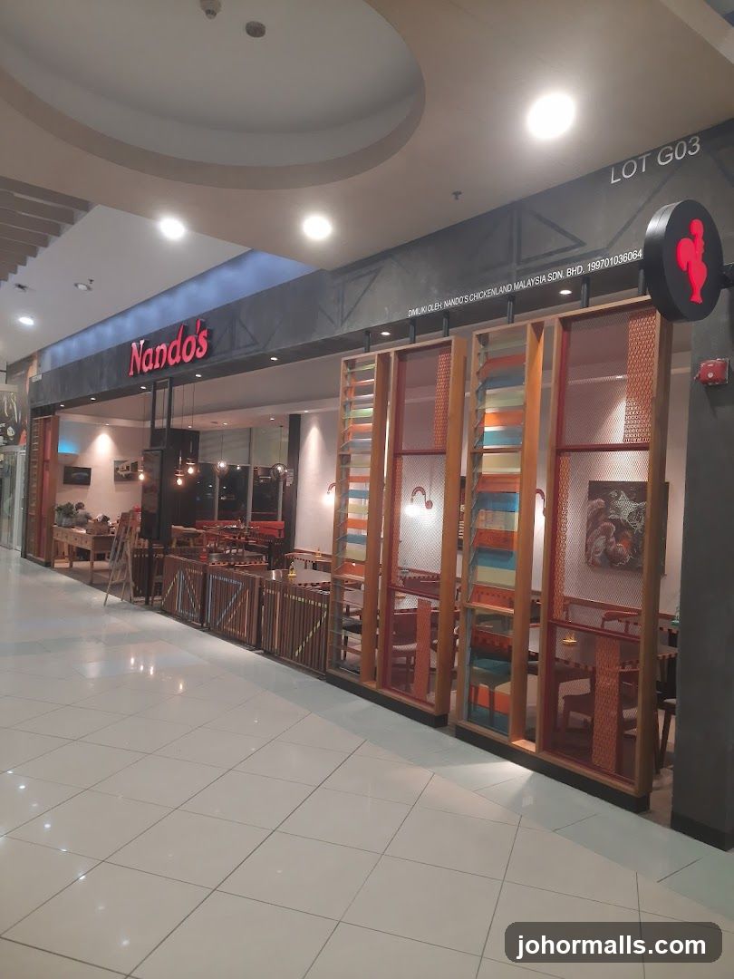 The exterior of a Nando's restaurant with its distinctive red logo and signage visible. The entrance area features decorative wooden screens and seating visible through the windows.