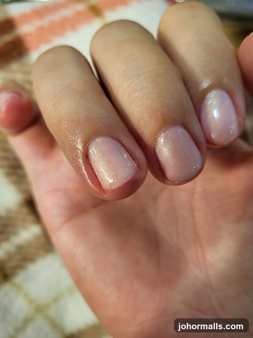 Close-up of a hand with light pink, shimmery nail polish