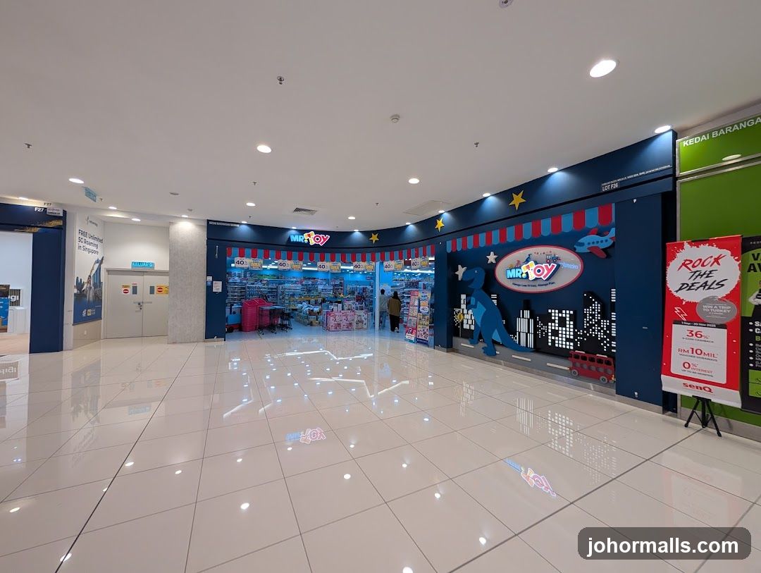 The exterior of a Mr. Toy store, a toy shop, is visible. The store has a blue facade with colorful decorations including a dinosaur, a cityscape, and a red bus. The Mr. Toy logo is prominently displayed. Inside the store, shelves stocked with toys are visible. A promotional banner for "Rock the Deals" is displayed to the right of the entrance.