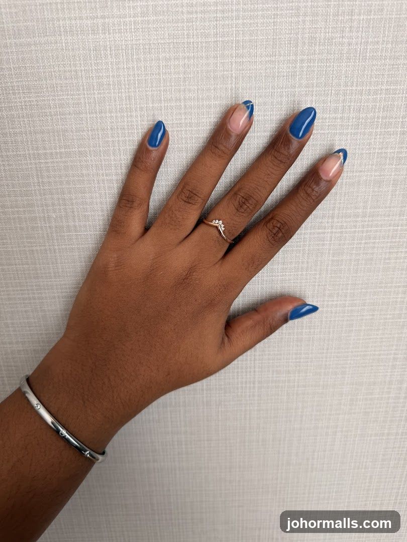 Hand with blue French tip nails and jewelry