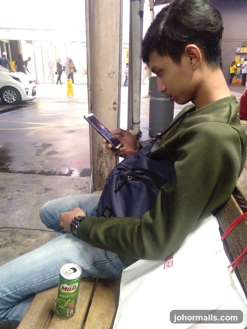 Man on bench with phone and drink