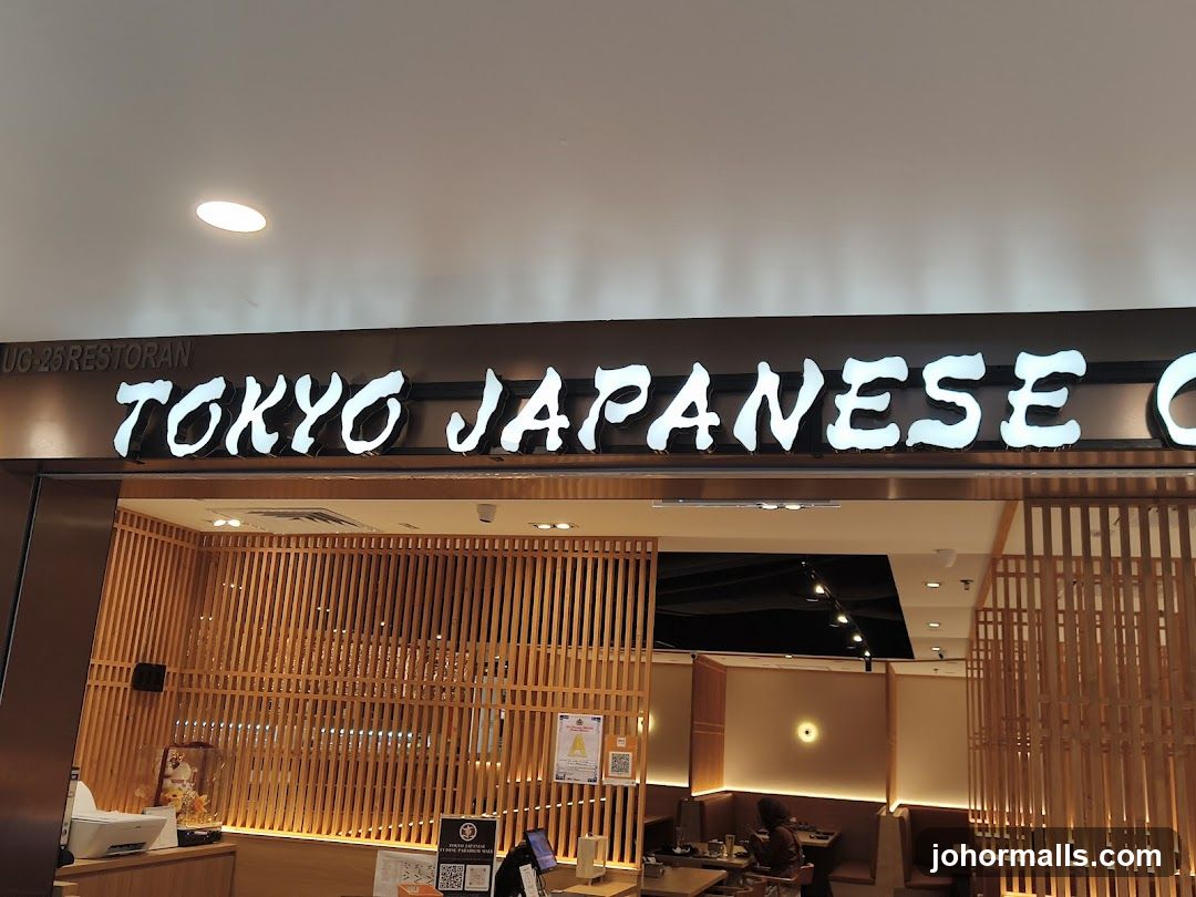 The exterior of a Japanese restaurant with a large illuminated sign that reads "TOKYO JAPANESE". Below the sign, the entrance features a wooden slatted facade and interior seating areas are visible.