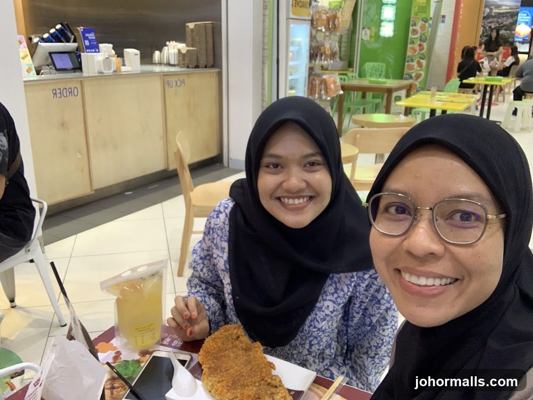 Two women smiling at the camera in a food court