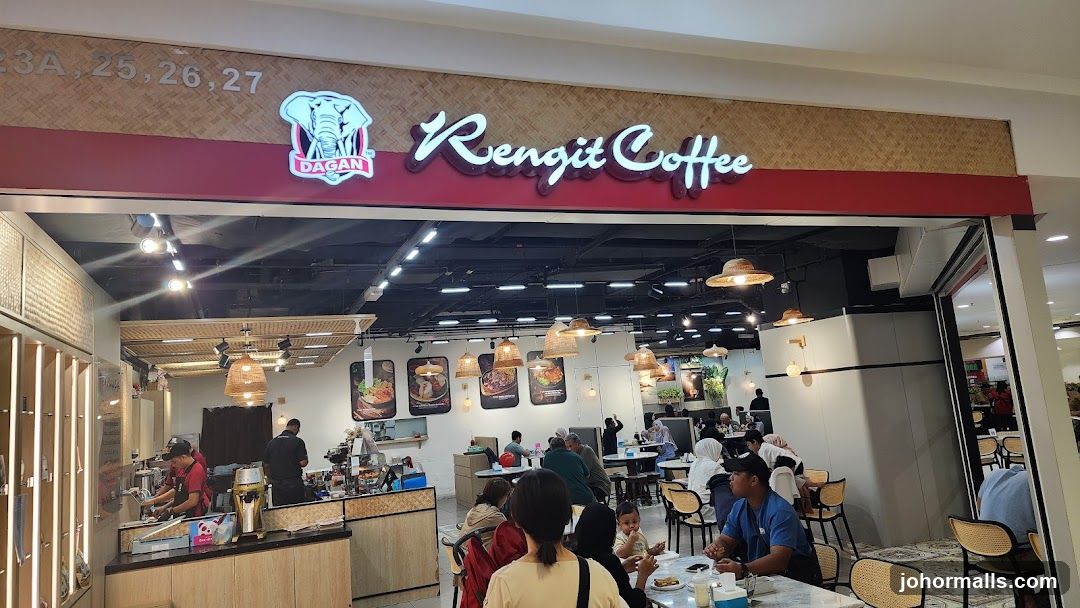 The exterior of a Rengit Coffee shop. The shop has a large red sign with white lettering that says "Rengit Coffee". Above the sign, there is a bamboo-patterned wall with the numbers "23A, 25, 26, 27" and a logo of an elephant with the word "Dagan" below it. The entrance is open, revealing the interior of the coffee shop with tables, chairs, and customers.
