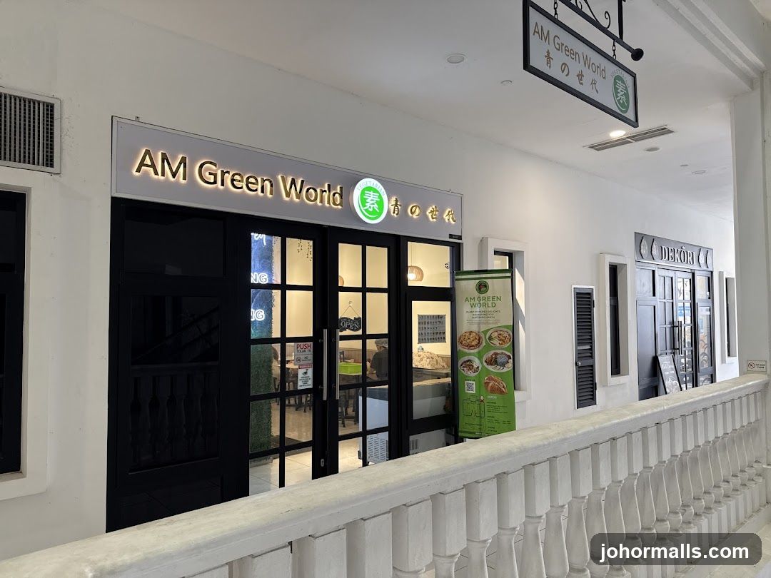 The storefront of AM Green World, a restaurant with a sign above the entrance. The entrance has glass doors and windows. A green banner with food images and text is displayed to the right of the entrance.