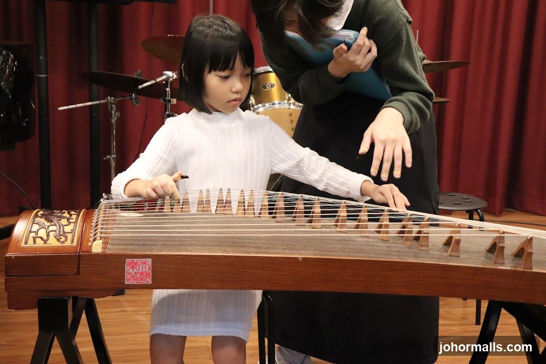 Child playing guqin with instructor