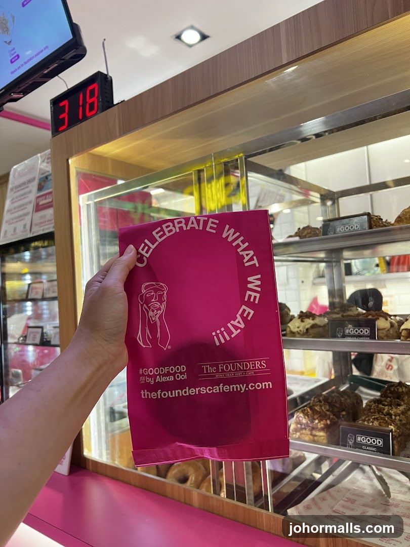 Hand holding branded paper bag at café counter
