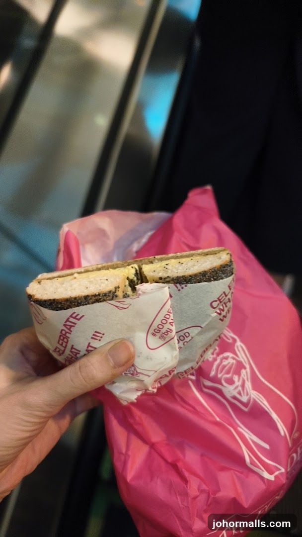 Hand holding a bagel wrapped in paper
