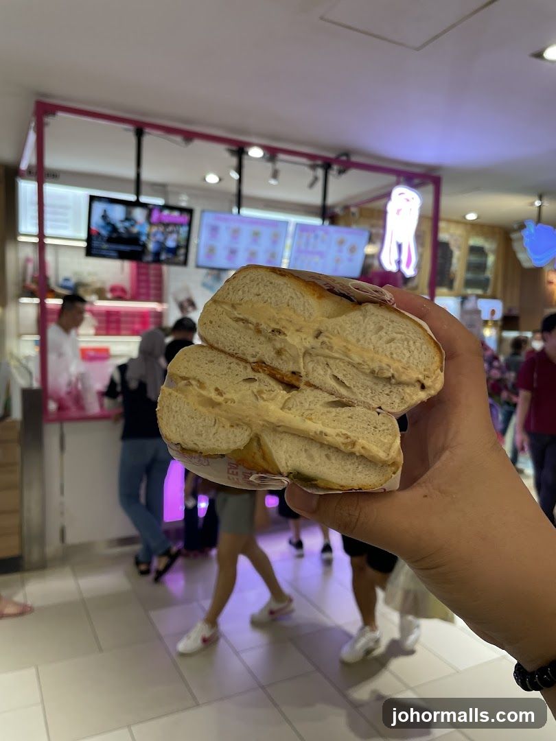 Hand holding a sliced bagel in a food court