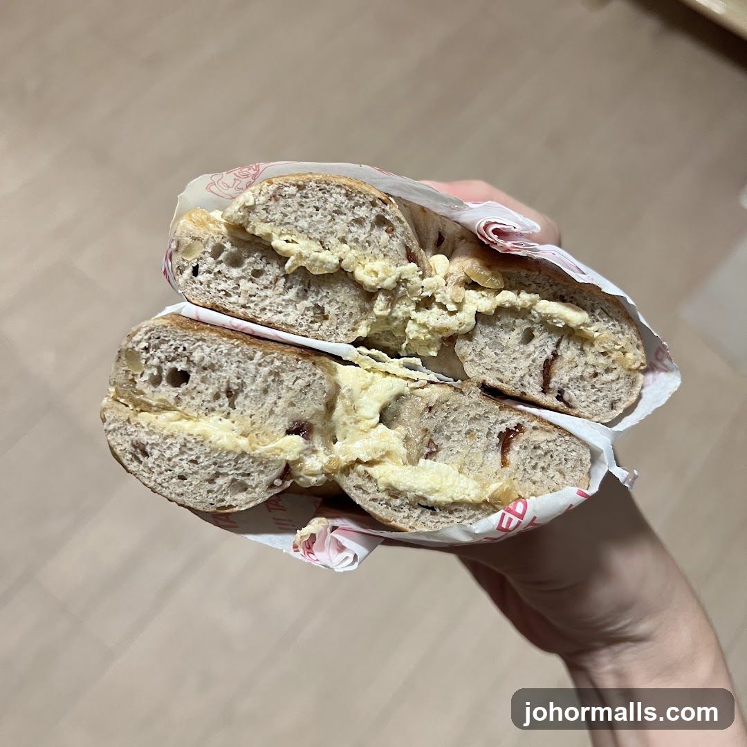 Hand holding a sliced bagel sandwich