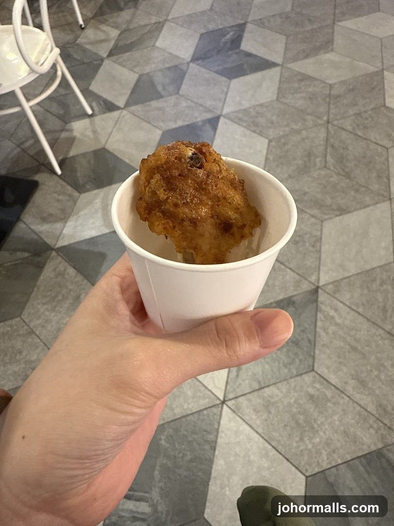 Hand holding fried food in paper cup