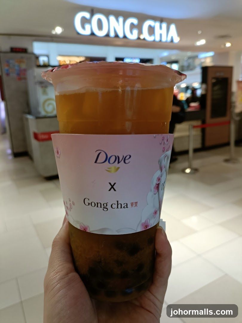 Hand holding a Gong Cha drink with Dove branding