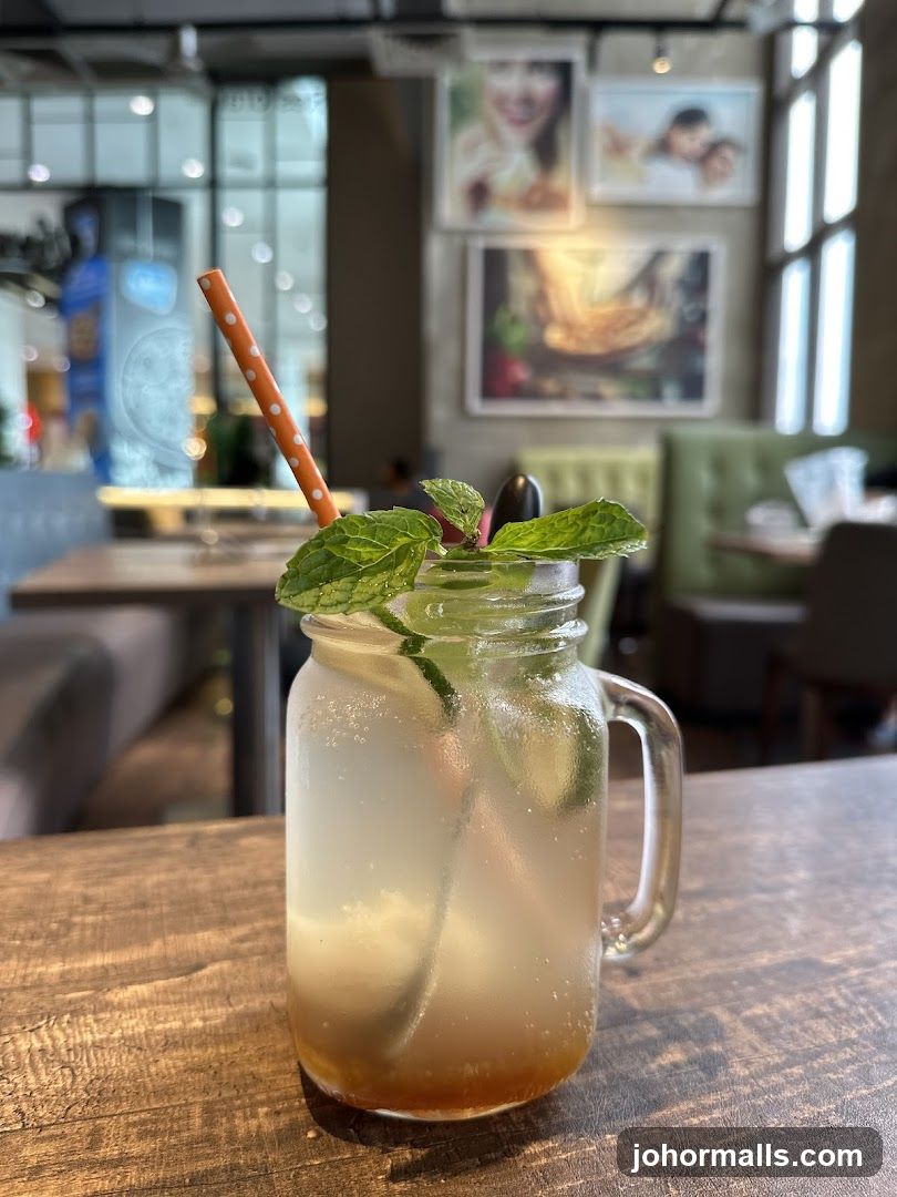 Mint-infused beverage in mason jar with orange polka-dot straw