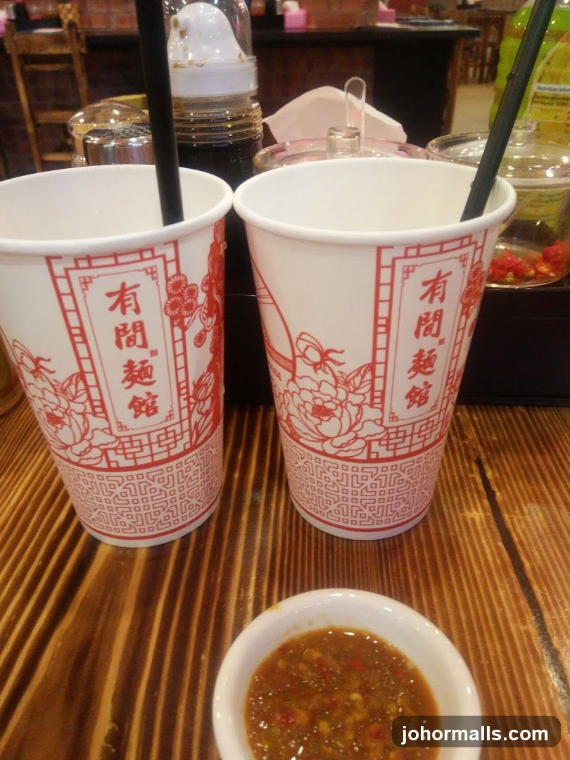 Two cups with Chinese characters and a small bowl of sauce