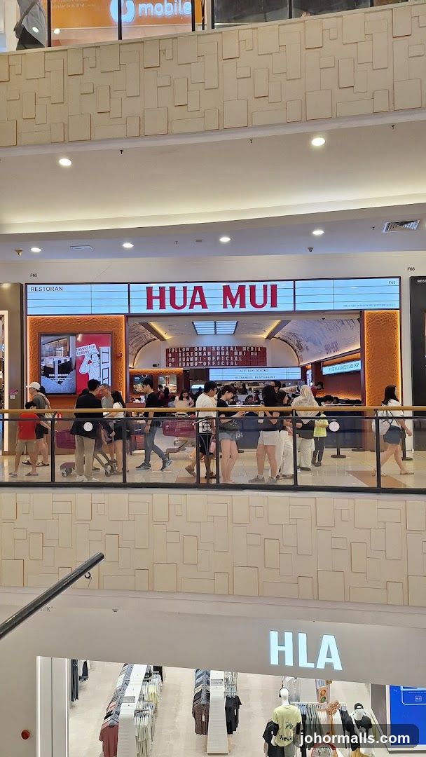 The exterior of a restaurant called Hua Mui, with its name prominently displayed in large red letters above the entrance. The restaurant appears to be located in a shopping mall, with other shops visible below. People are seen queuing outside the restaurant.