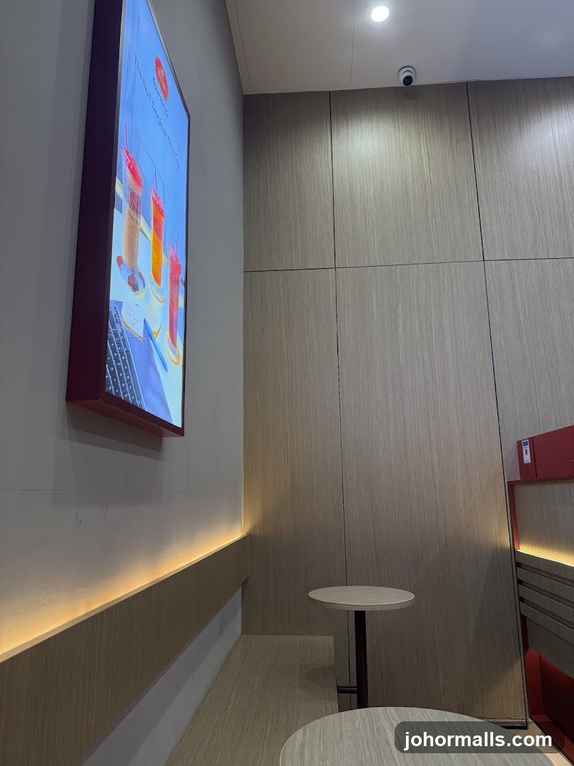 Interior of a cafe with a digital menu board and seating