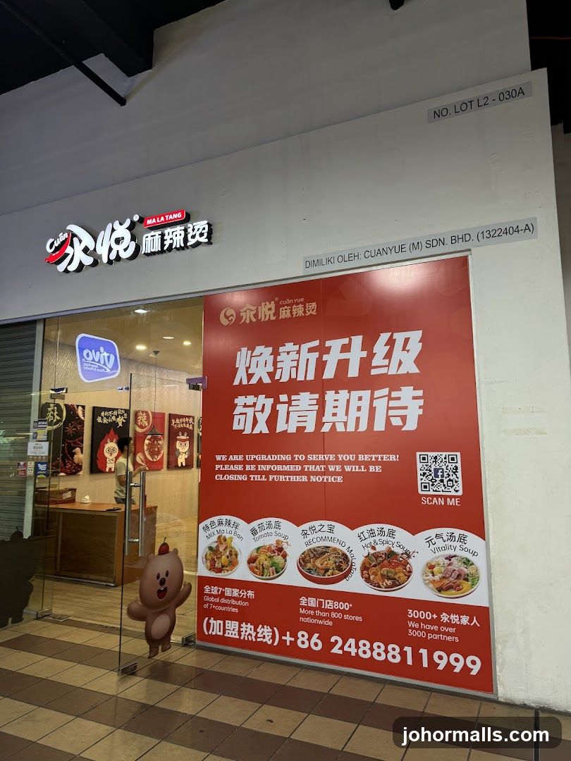 The exterior of a Mala Tang restaurant with a large red sign announcing an upgrade and temporary closure. The sign features images of different soup bases and contact information. The restaurant's name and logo are visible above the entrance.