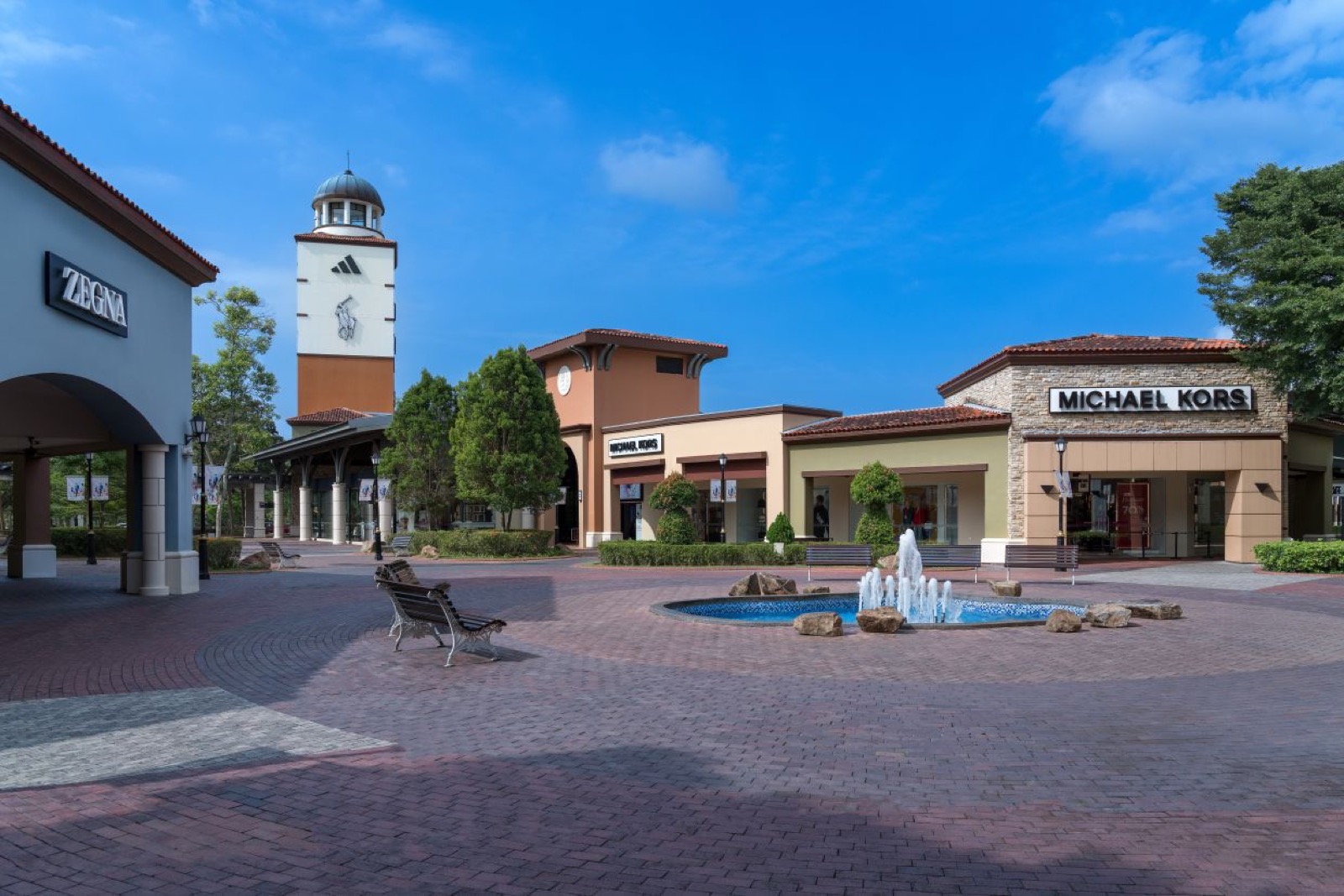 Johor Premium Outlets courtyard fountain with Michael Kors and Zegna stores during the 2026 shopping season